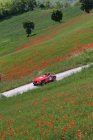 Повітряний вид на червону машину, що їде по сільській місцевості Монтефельтро, Урбіно, Марче, Італія, Європа — стокове фото
