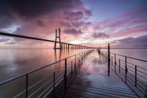 Cores do nascer do sol as nuvens refletidas no rio Tejo e enquadram a ponte Vasco da Gama em Lisboa, Estremadura, Portugal, Europa — Fotografia de Stock