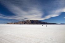 Two people run on the surface of Salar de Uyuni the largest salt desert in the world, South Lipez landscape, Bolivia, South America — Stock Photo