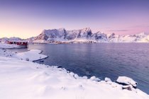 Los colores del amanecer enmarcan las casas de pescadores rodeadas de mar congelado Reine Bay Nordland, Islas Lofoten, Noruega, Europa - foto de stock