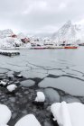 Mar gelado e picos nevados em torno das casas típicas chamadas rorbu e barcos de pesca Hamn paisagem, Ilhas Lofoten, Norte da Noruega, Europa — Fotografia de Stock