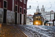 Острая атмосфера на старых улицах Альфамы с замком на заднем плане и трамваем номер 28, Альфама, Лисбон, Португалия, Европа — стоковое фото