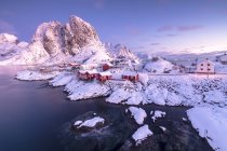 Rosafarbener Sonnenaufgang auf schneebedeckten Gipfeln, umgeben vom gefrorenen Meer rund um das Dorf Hamnoy Nordland, Landschaft der Lofoten, Norwegen, Europa — Stockfoto