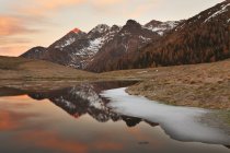 El grupo Tre Signori se refleja en un pequeño lago en las llanuras de Avaro, valle de Brembana, Lombardía, Italia - foto de stock