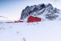 Des sommets enneigés entourent les maisons de pêcheurs typiques appelées Rorbu en hiver Eggum Vestvagy Island, Lofoten Islands landscape, Norvège, Europe — Photo de stock