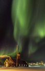 Luci del Nord sopra la Chiesa di Sion. Città Ilulissat sulla riva della baia di Disko nella Groenlandia occidentale, centro per il turismo, l'amministrazione e l'economia. Il fiordo di ghiaccio nelle vicinanze è elencato come patrimonio mondiale dell'UNESCO. America, Nord America, Groenlandia, Danimarca — Foto stock