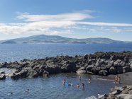 Strand im Lavastrom in der Nähe von Criacao Velha, Faial Insel im Hintergrund. pico island, eine Insel in den Azoren (ilhas dos acores) im Atlantik. die azoren sind eine autonome region portugals. europa, portugal, azoren — Stockfoto
