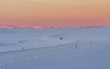 Strada di campagna solitaria durante l'alba nelle montagne innevate dell'Islanda. Europa, Europa settentrionale, Italia, febbraio — Foto stock