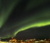 Northern Lights sobre a cidade e congelado Disko Bay. Cidade Ilulissat na costa da Baía de Disko, na Groenlândia Ocidental, centro de turismo, administração e economia. O fiorde de gelo nas proximidades está listado como patrimônio mundial da UNESCO. América do Norte, Gronelândia — Fotografia de Stock