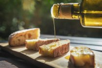 Gros plan de verser de l'huile d'olive sicilienne sur le pain — Photo de stock