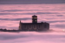 Basilika des hl. Franziskus, bei Sonnenuntergang mit der Stadt im Nebel, assisi, umbrien, italien, europa — Stockfoto