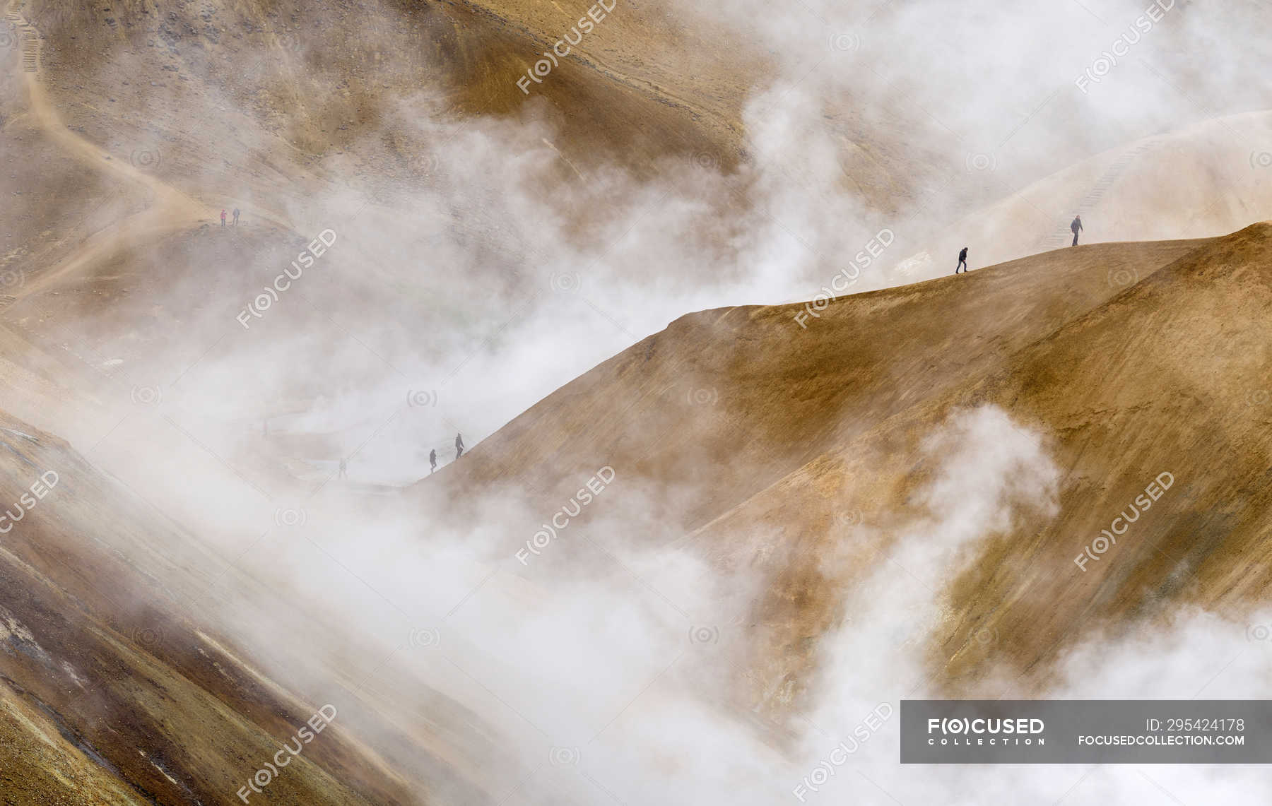 Hikers in the geothermal area Hveradalir in the mountains ...