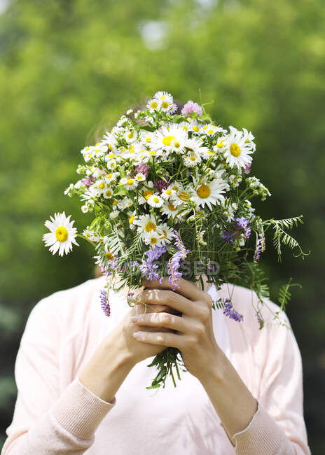 Ein junges Mädchen hält einen Strauß Wildblumen in den Händen — Stockfoto