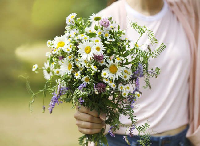 A young girl holding a bouquet of wildflowers in hands — Stock Photo