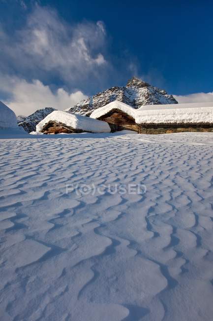 Le vent façonne la neige qui est tombée entre les cabanes traditionnelles de l'Alpe Prabello, vallée du Malenco, Valtellina, Lombardie, Italie, Europe — Photo de stock