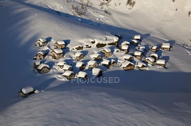 Vista aérea de las cabañas de montaña de Lendine Alp después de una fuerte nevada de invierno, Valchiavenna, Valtellina, Lombardía, Italia, Europa - foto de stock