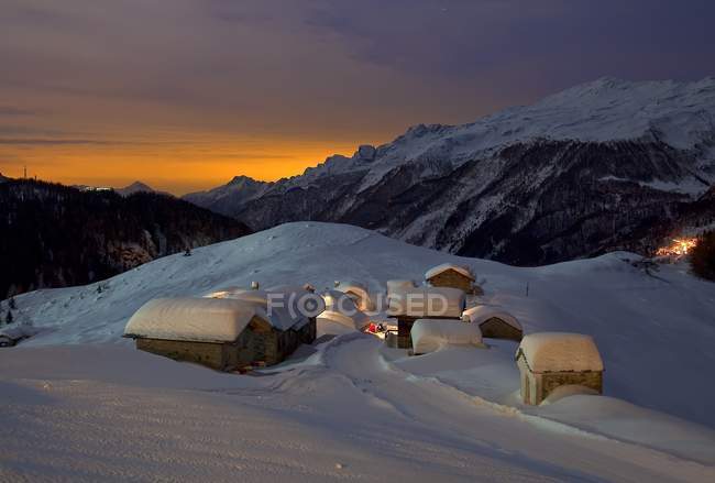 Las cabañas de montaña de los Alpes Andossi en una noche de luna llena, Chiavenna, Valchiavenna, Vallespluga, Valtellina, Lombardía, Italia, Europa - foto de stock
