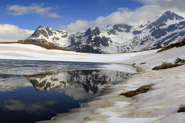 Lago degli Andossi si scioglie a fine primavera, con riflesso del Gruppo Suretta, Vall Spluga, Lombardia, Italia, Italia — Foto stock