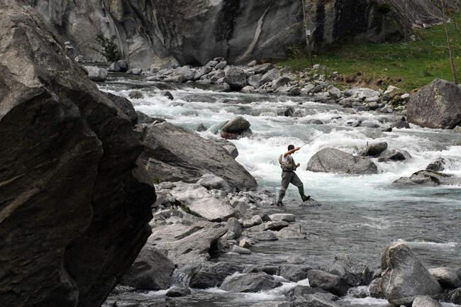 Pescador lanza su línea en las frías aguas del arroyo Masino, Valmasino, Valtellina, Lombardía, Italia, Europa - foto de stock
