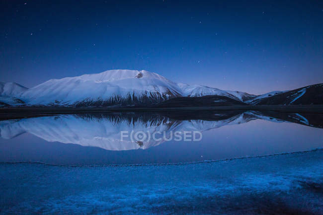 Beautiful landscape in Castelluccio di Norcia during a frozen sunset on Mount Redentore reflected in the lake, Umbria, Italy — Stock Photo
