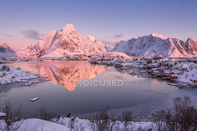 Snowy peaks are reflected in the frozen sea at sunset Reine Bay Nordland, Lofoten Islands landscape, Norway, Europe — Stock Photo