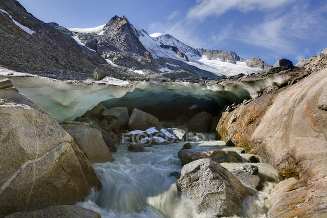 The glacier snout with ice cave of Viltragenkees in the National Park Hohen Tauern. Viltragenkees  is showing signs of rapid retreat. Its snout is flat and covered with moraine.The glacier foreland shows fresh moraine till. Mt Kleinvenediger in the b — Stock Photo