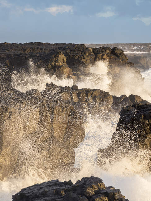 Línea costera en Brimketill durante condiciones tormentosas al atardecer. La costa del Atlántico norte en la península de Reykjanes durante el invierno. Norte de Europa, Escandinavia, Islandia, febrero - foto de stock
