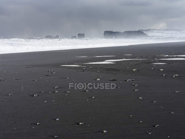 La costa del Atlántico norte cerca de Vik y Myrdal durante el invierno. Playa negra volcánica Reynisfjara, vista hacia Dyrholaey. Europa, norte de Europa, Escandinavia, Islandia, febrero - foto de stock