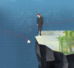 Бизнесмен на скале рассматривает разбитую банкноту евро в линейном графике — стоковое фото