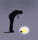 Uomo guardando verso il basso sulla lampadina incandescente — Foto stock