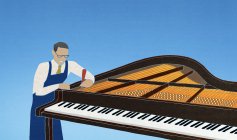 Trabalhador afinação piano no fundo azul — Fotografia de Stock