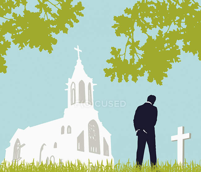 Hombre visitando cementerio cerca de la iglesia - foto de stock