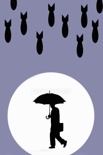 Bombs falling on businessman holding an umbrella — Stock Photo