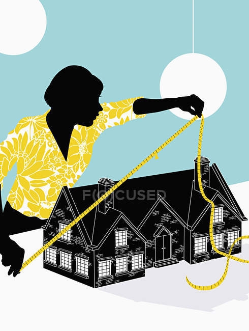 Женщина измеряет дом на синем фоне — стоковое фото