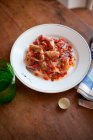 Жареный кальмар с помидорами черри подается на тарелке на деревянном столе — стоковое фото