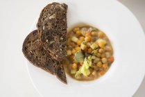 Sopa de grão de bico e legumes servida com fatias de pão, vista superior . — Fotografia de Stock