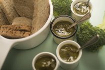 Cups of fresh broccoli puree with bowl of sliced bread. — Stock Photo