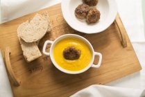 Pumpkin cream soup with fried rice balls with bread slices on wooden tray. — Stock Photo