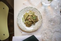 Паста из цельной муки со сливочным соусом из рукколы с базиликом и кедровыми орехами на винтажной тарелке — стоковое фото