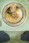 Вид сверху на тарелку со сливками из фасоли, козьим сыром и кусочком хлеба . — стоковое фото
