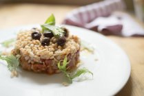 Gerstenkuchen mit würzigem Soja-Eintopf und marinierten Oliven auf Teller. — Stockfoto