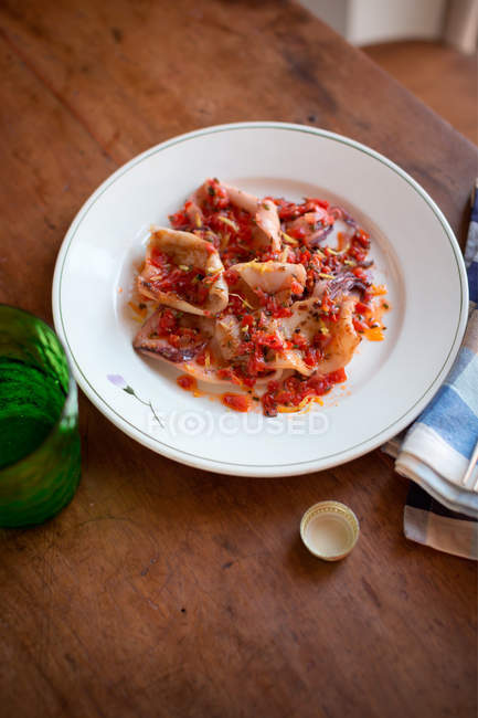 Calamares a la parrilla con tomates cherry servidos en plato sobre mesa de madera - foto de stock