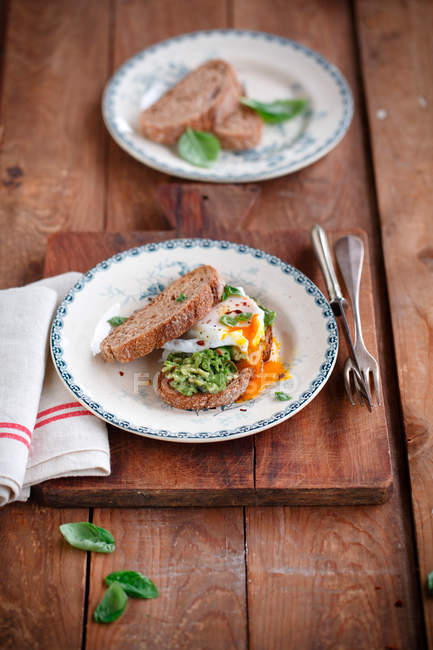 Avocado con pane di segale e uova servito sul piatto su tavola di legno — Foto stock