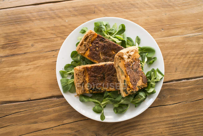 Sliced tasty squash casserole with turmeric and spinach leaves. — Stock Photo