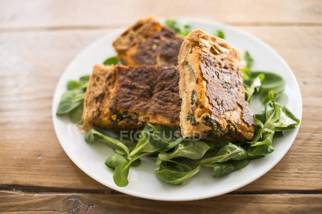 Sliced tasty squash casserole with turmeric and spinach leaves. — Stock Photo
