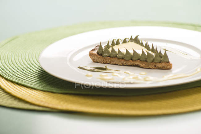 Короткий торт с ломтиком фисташкового крема на тарелке — стоковое фото
