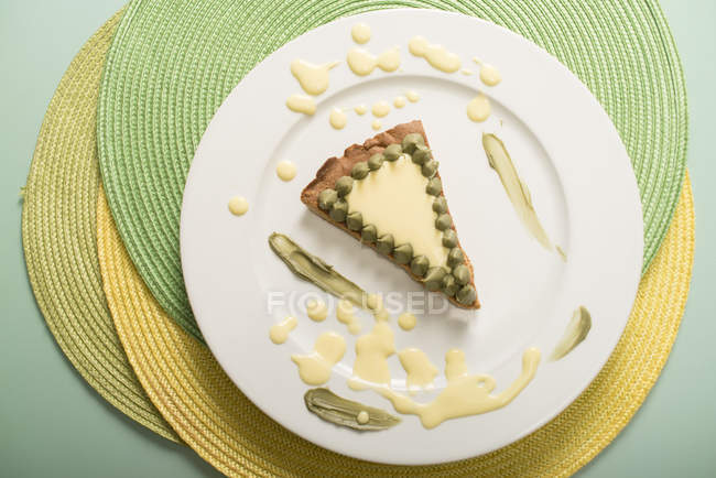Tarta corta con rodaja de crema de pistacho en el plato, vista superior - foto de stock