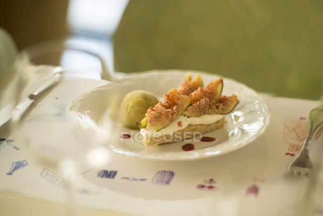 Тарелка ржаного пирога с йогуртом и инжиром подается на стол со столовыми приборами . — стоковое фото