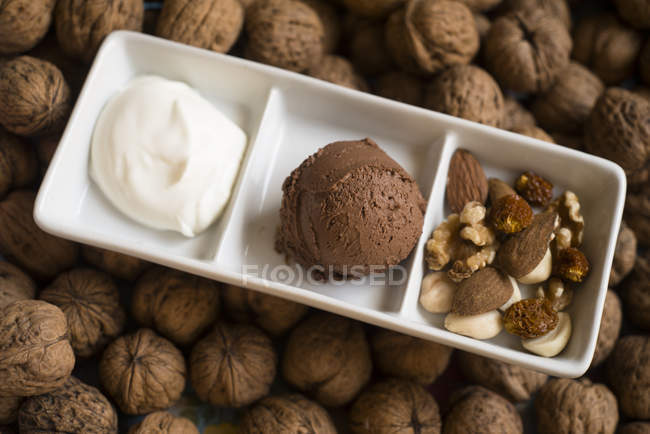 Plate with chocolate mousse, whipped cream and dried fruits and nuts. — Stock Photo