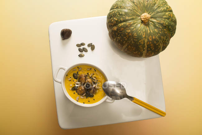 Pumpkin and chestnut cream soup in bowl on table with whole pumpkin — Stock Photo
